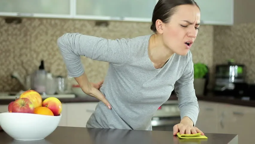 کمردرد زن پشت اپن آشپزخانه کنار ظرف میوه