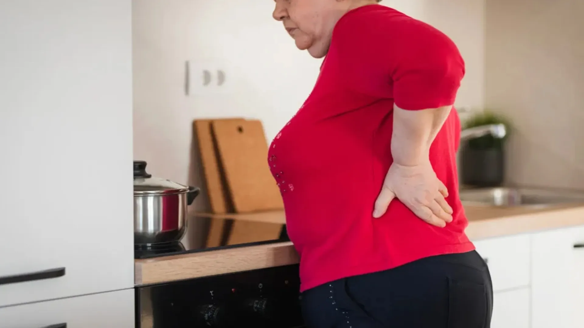 کمردرد زن چاق لباس قرمز در آشپزخانه